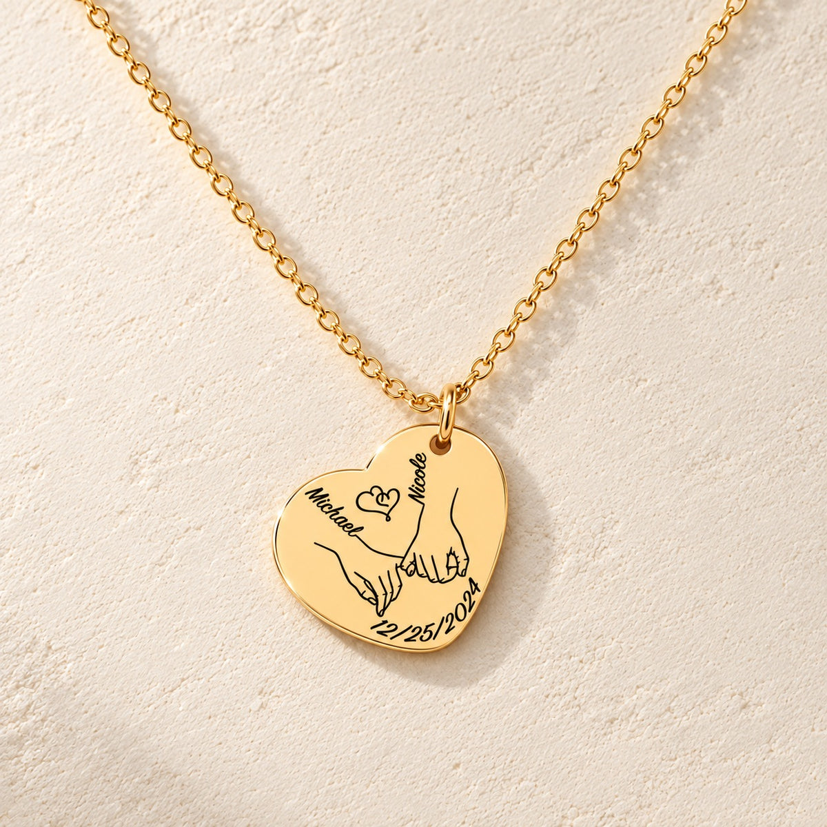 Détail de la médaille en cœur dorée avec deux mains liées, prénoms Michael et Nicole et date 12/25/2024.