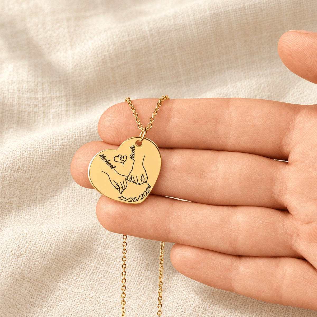 Collier Coeur Notre Premier Noël Ensemble personnalisé doré tenu en main, détail de la gravure.