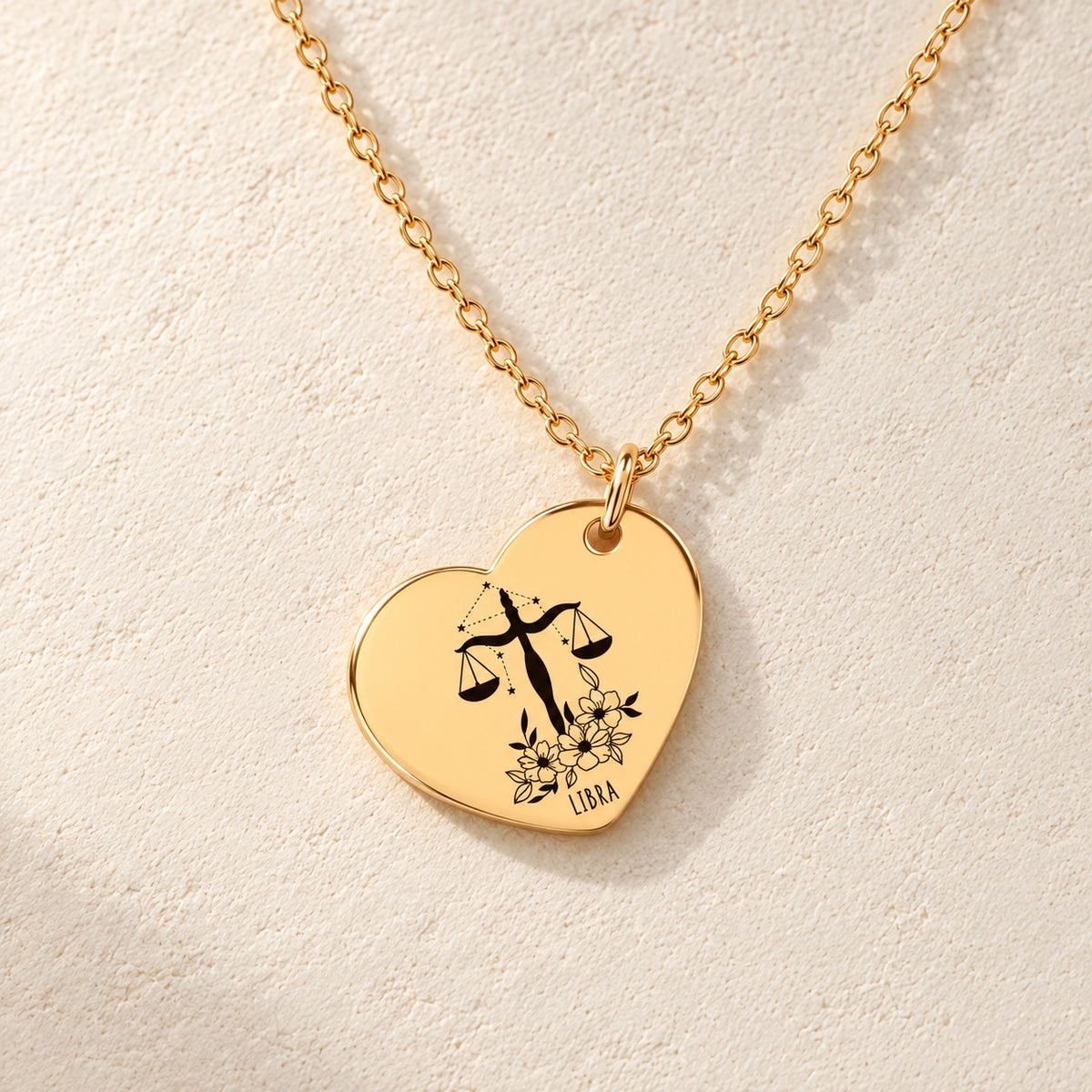 Détail de la médaille en cœur dorée avec motif du signe Balance et ornements.