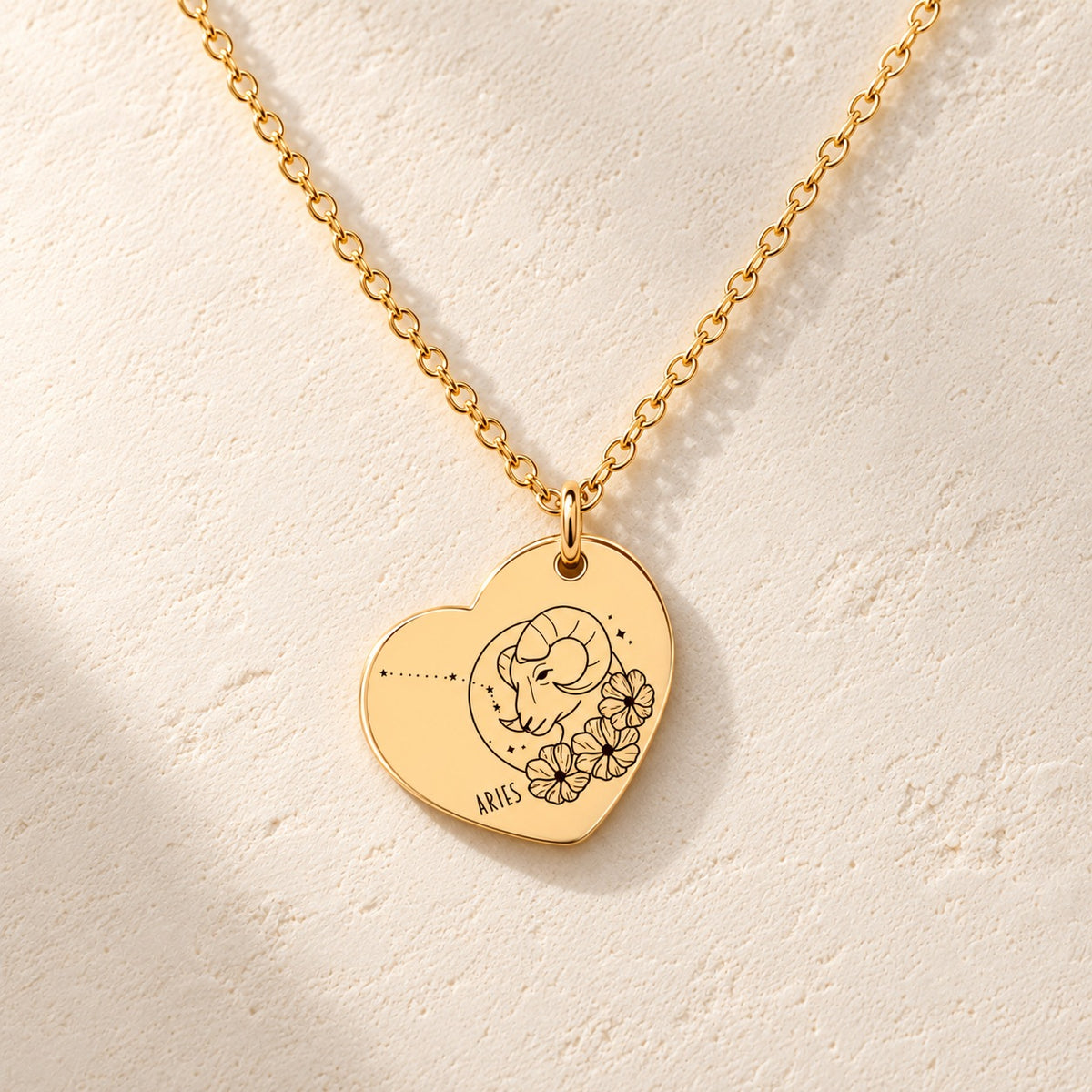 Détail de la médaille en cœur dorée avec motif du signe Bélier et ornements.