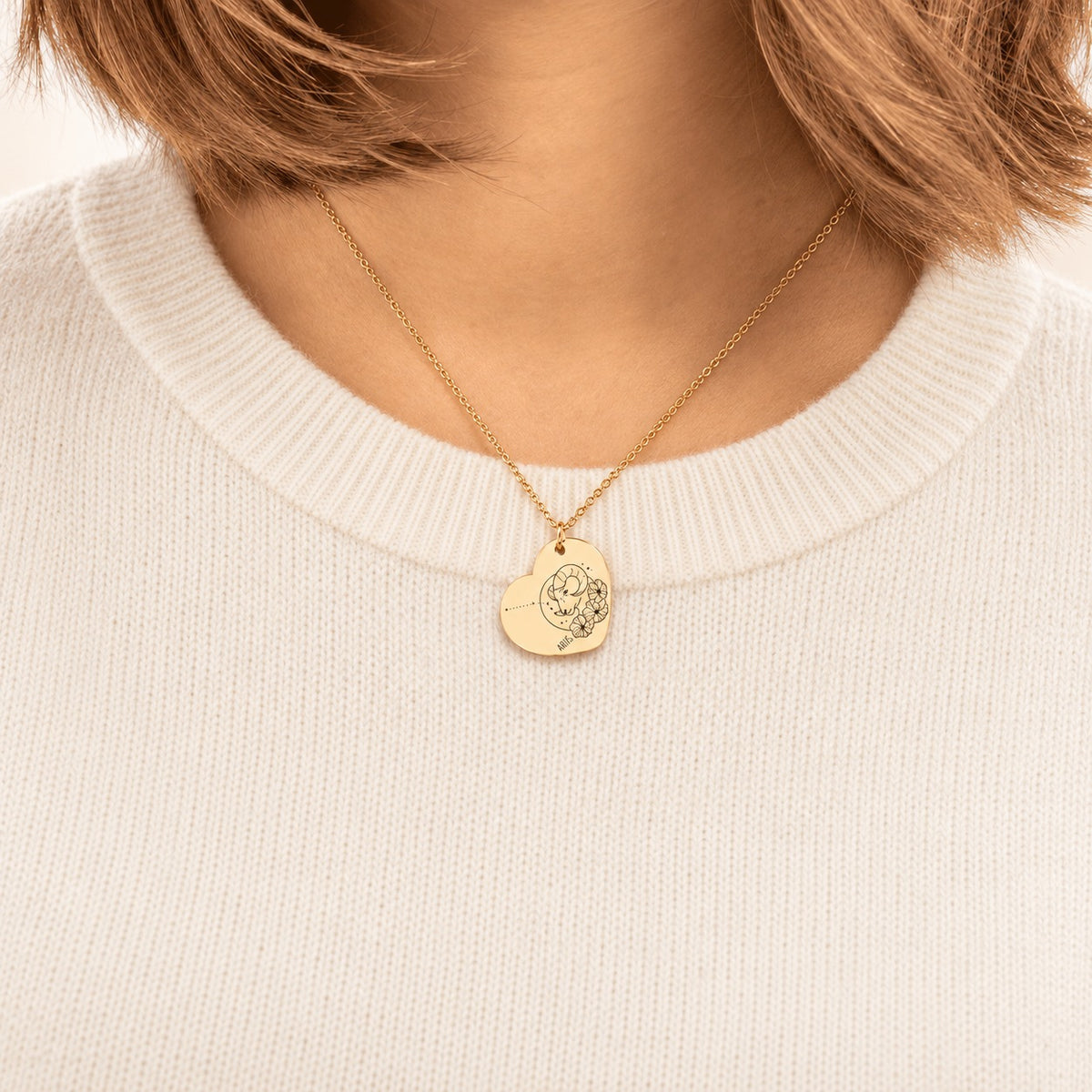 Collier cœur signe astrologique Bélier doré porté au cou, médaille en cœur gravée.