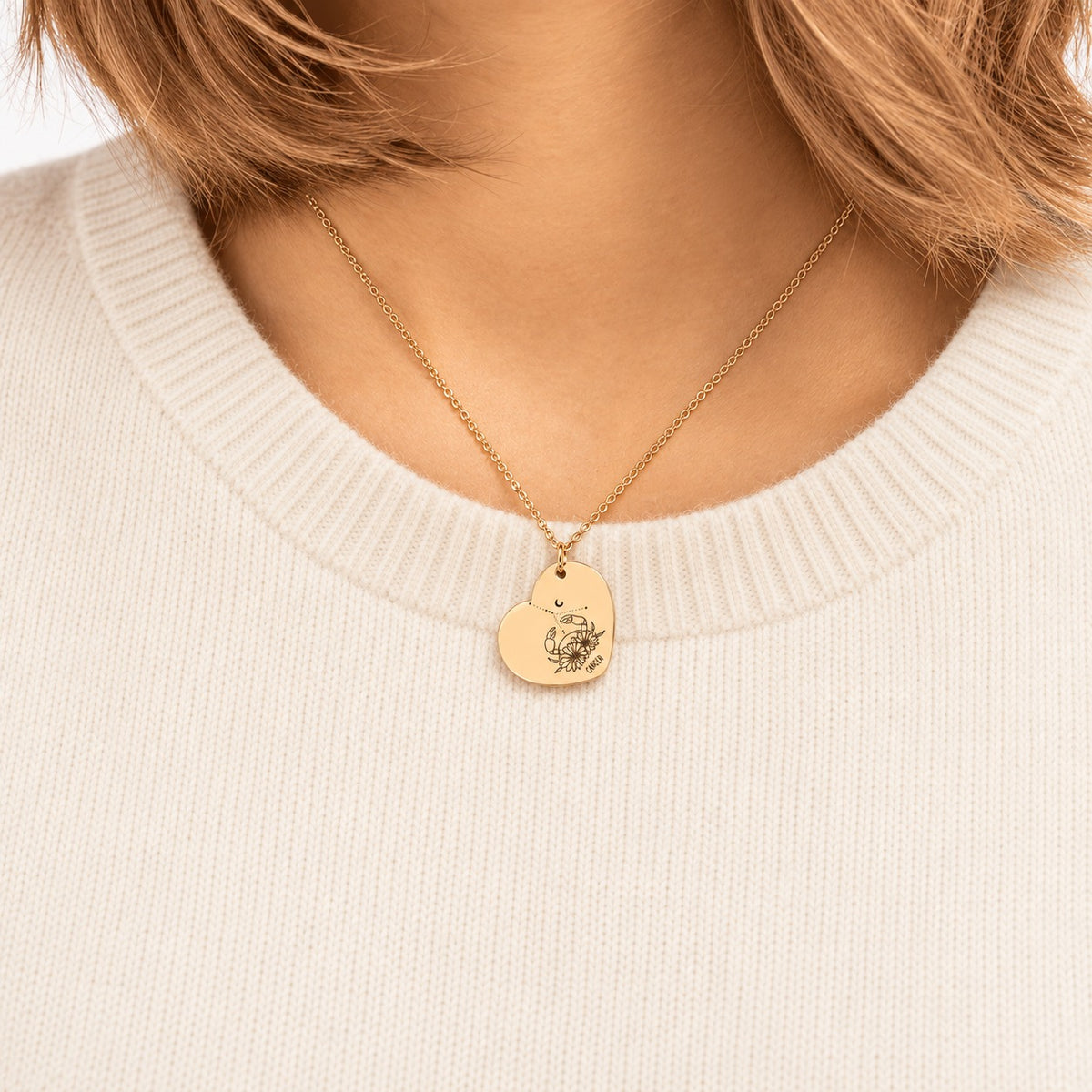 Collier cœur signe astrologique Cancer doré porté au cou, médaille en cœur gravée.