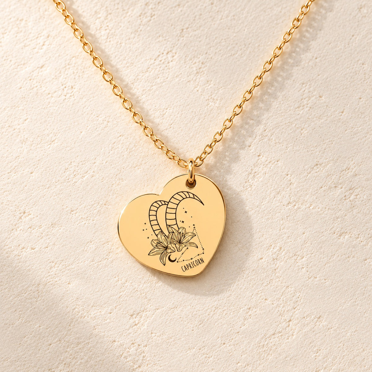 Détail de la médaille en cœur dorée avec motif du signe Capricorne et ornements.