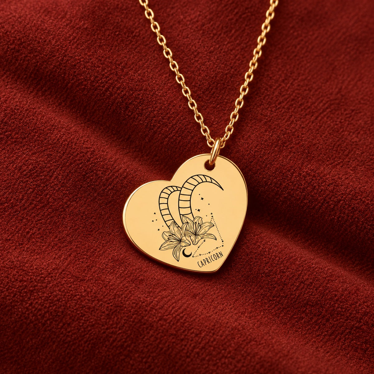 Médaille en cœur dorée avec motif du signe Capricorne et ornements, sur suédine rouge sanguine.
