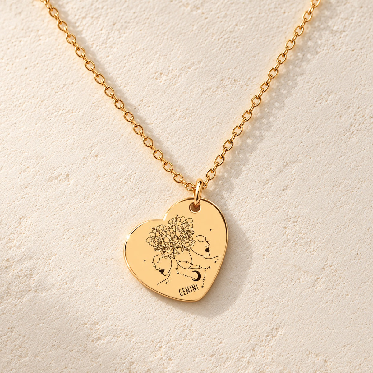 Détail de la médaille en cœur dorée avec motif du signe Gémeaux et ornements.