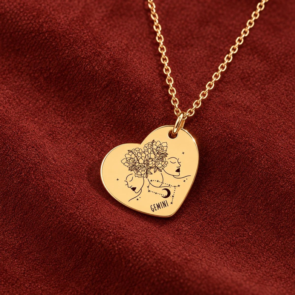 Médaille en cœur dorée avec motif du signe Gémeaux et ornements, sur suédine rouge sanguine.