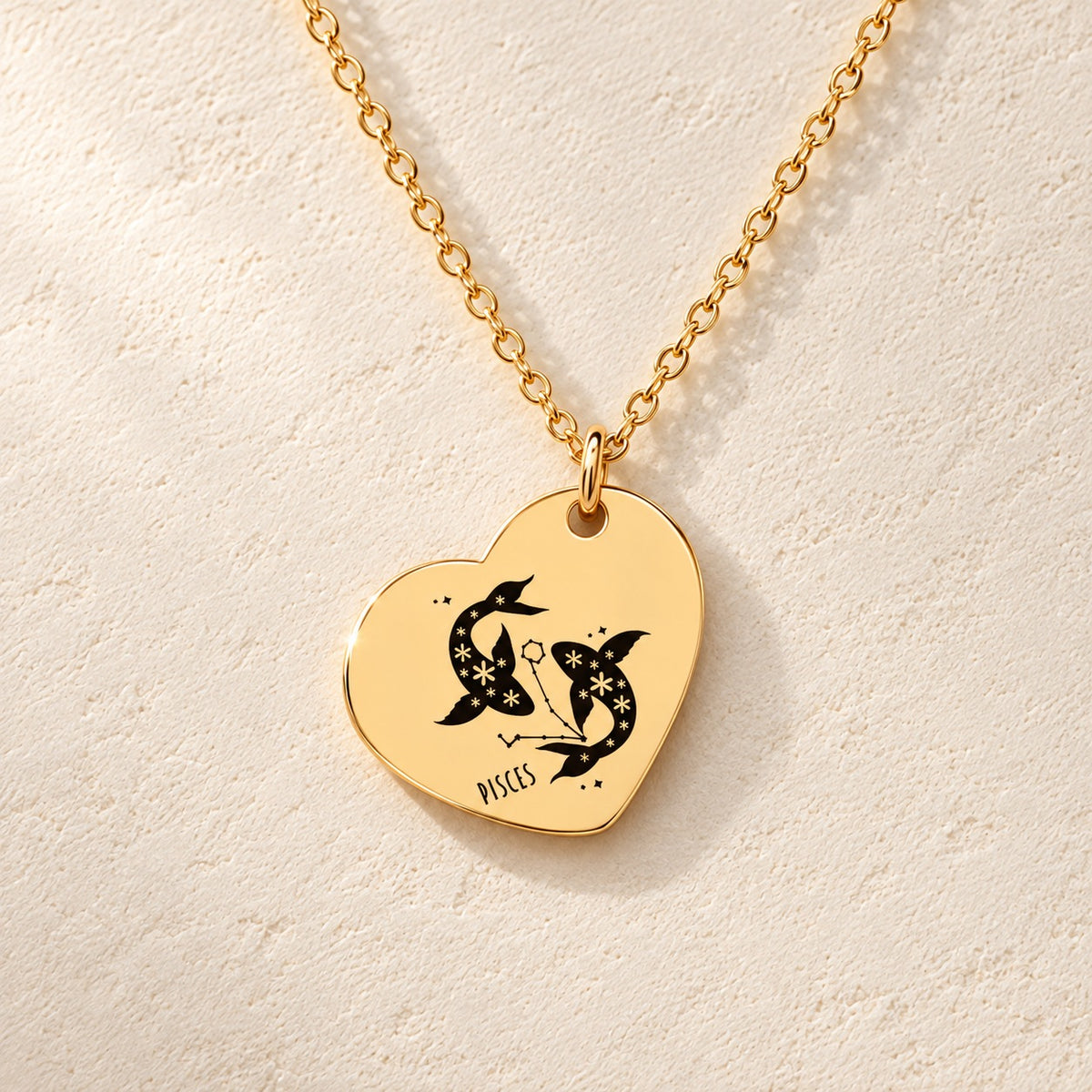 Détail de la médaille en cœur dorée avec motif du signe Poissons et ornements.