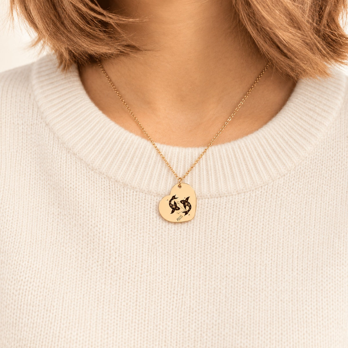 Collier cœur signe astrologique Poissons doré porté au cou, médaille en cœur gravée.