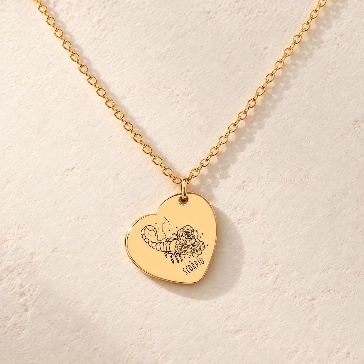 Détail de la médaille en cœur dorée avec motif du signe Scorpion et ornements.