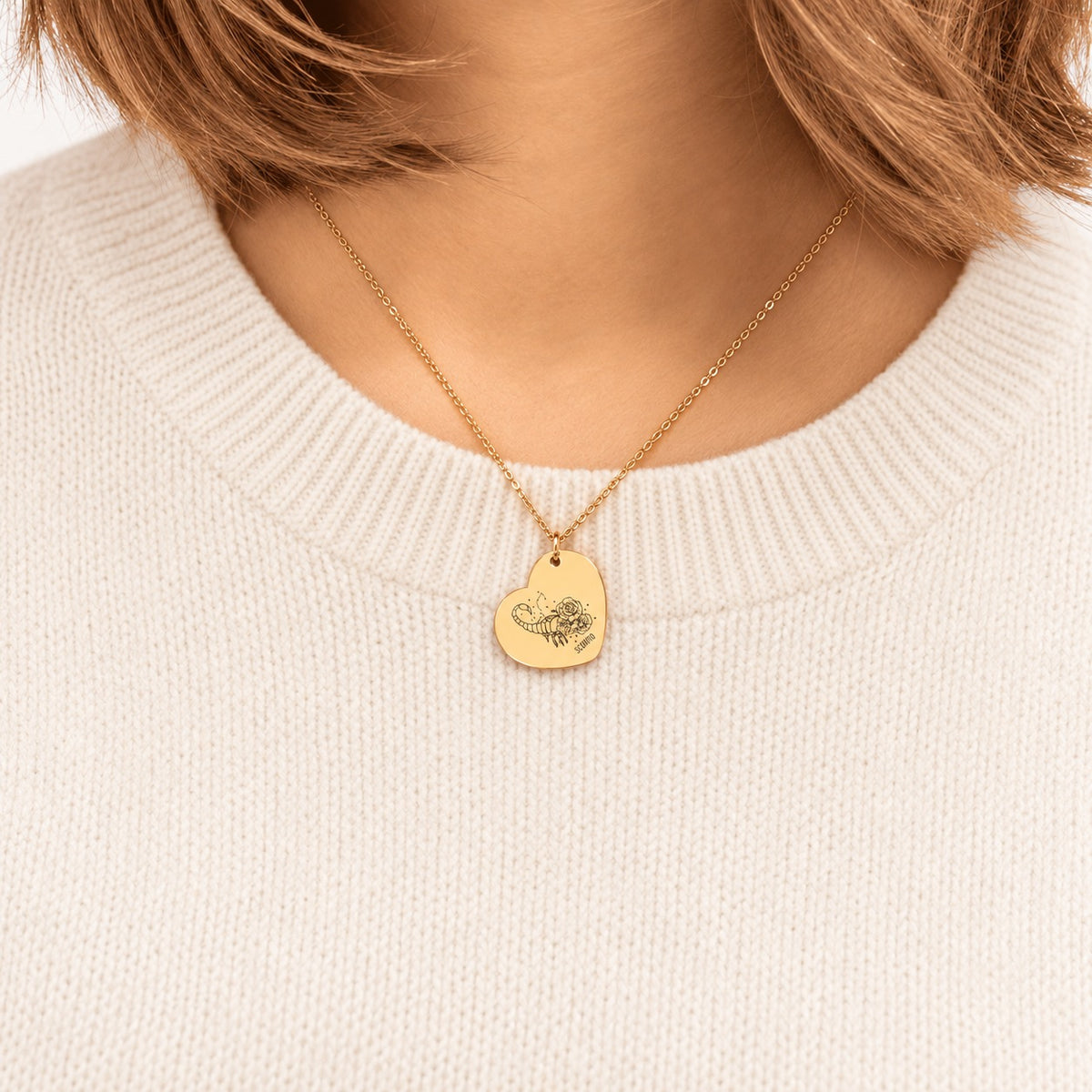 Collier cœur signe astrologique Scorpion doré porté au cou, médaille en cœur gravée.