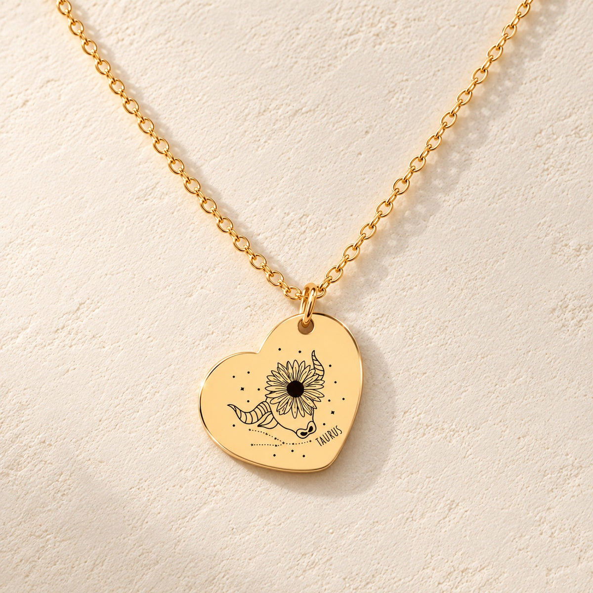 Détail de la médaille en cœur dorée avec motif du signe Taureau et ornements.