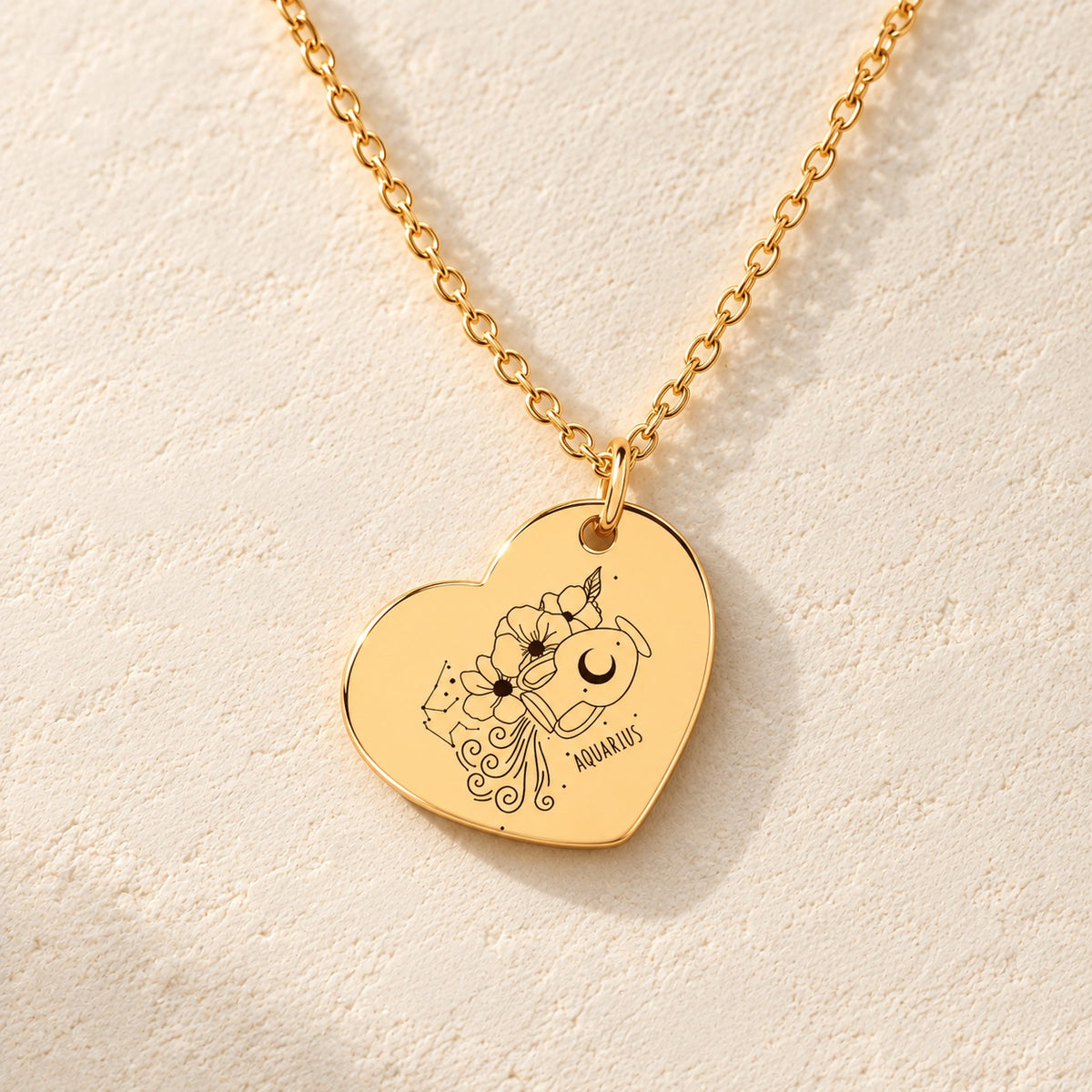 Détail de la médaille en cœur dorée avec motif du signe verseau et ornements.