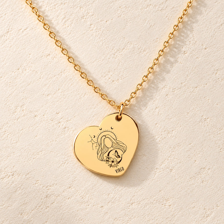 Collier cœur signe astrologique Vierge doré, médaille en cœur gravée avec motif du signe Vierge et ornements, sur fond ivoire.