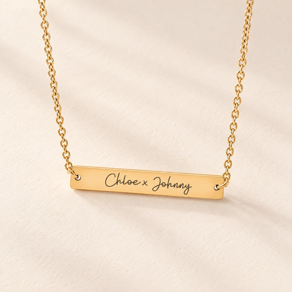 Collier Deux Prénoms doré, barrette gravée Chloe x Johnny sur fond ivoire.