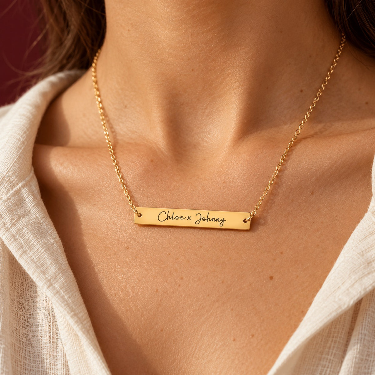 Collier Deux Prénoms doré porté au cou, avec barrette gravée Chloe x Johnny.