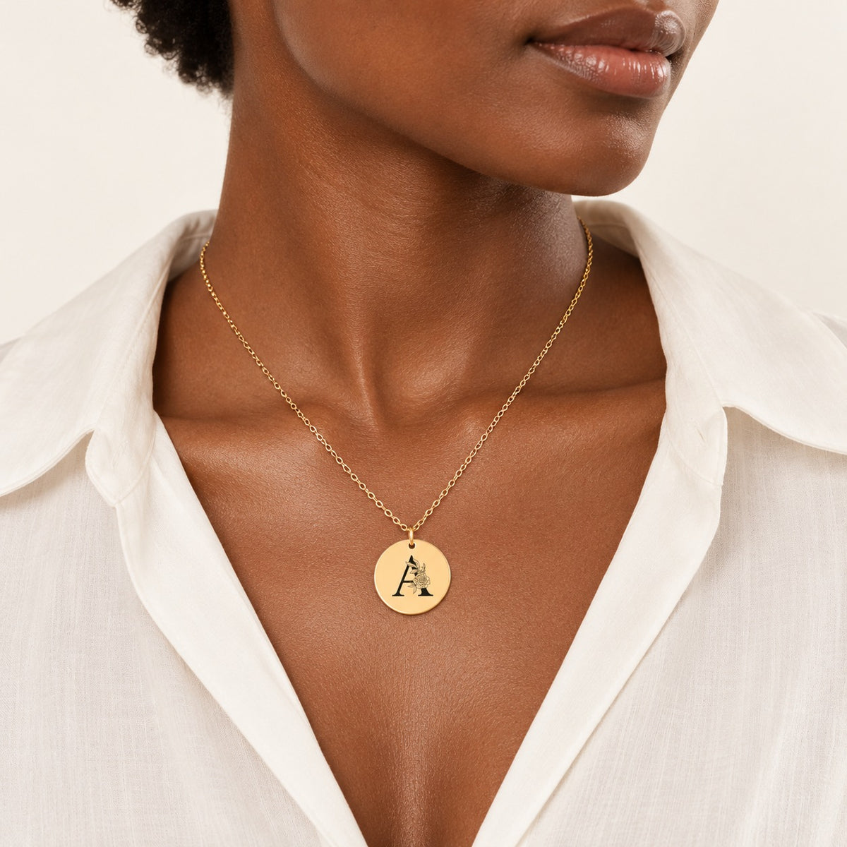Collier initiale florale A personnalisé doré porté au cou, médaille ronde gravée.
