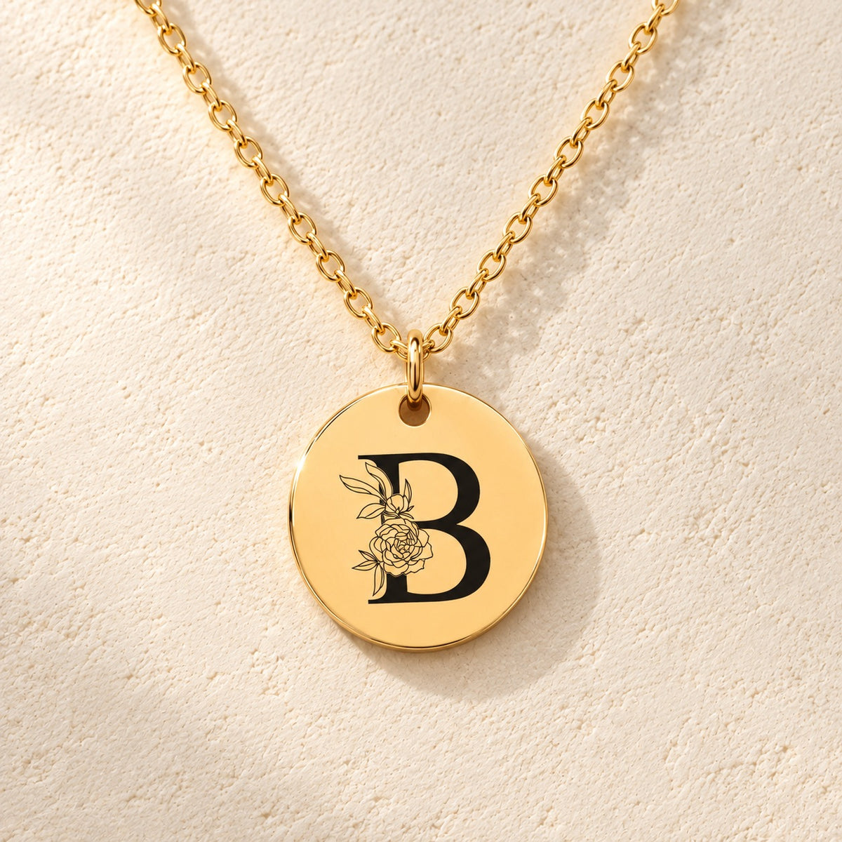 Détail de la médaille ronde dorée avec initiale B et fleurs.