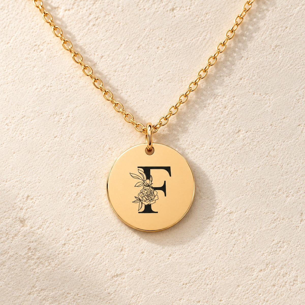 Détail de la médaille ronde dorée avec initiale F et fleurs.