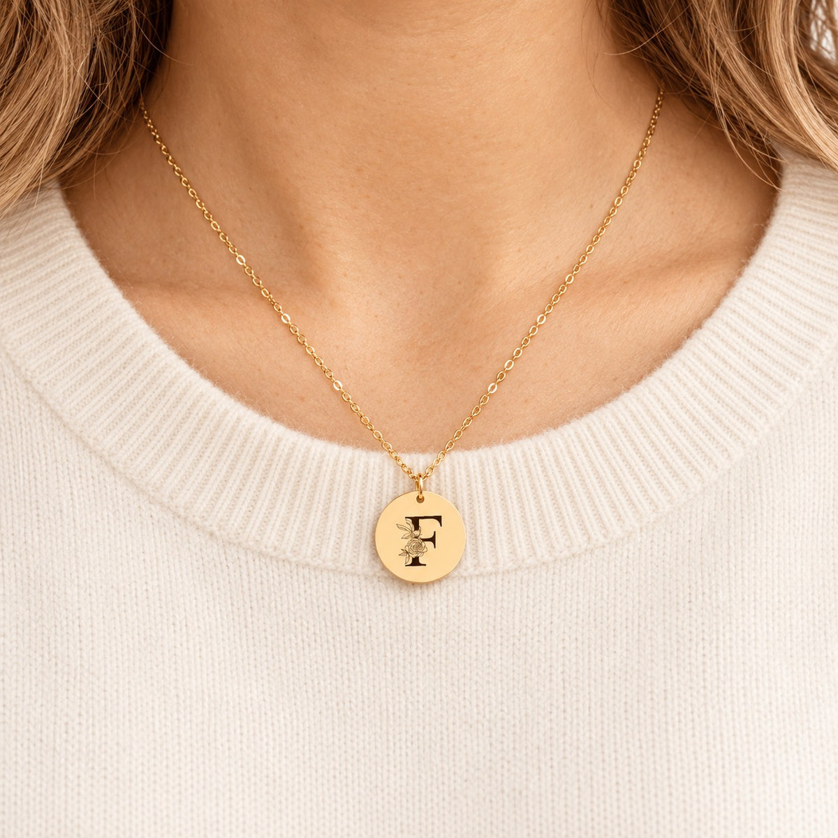 Collier initiale florale F personnalisé doré porté au cou, médaille ronde gravée.