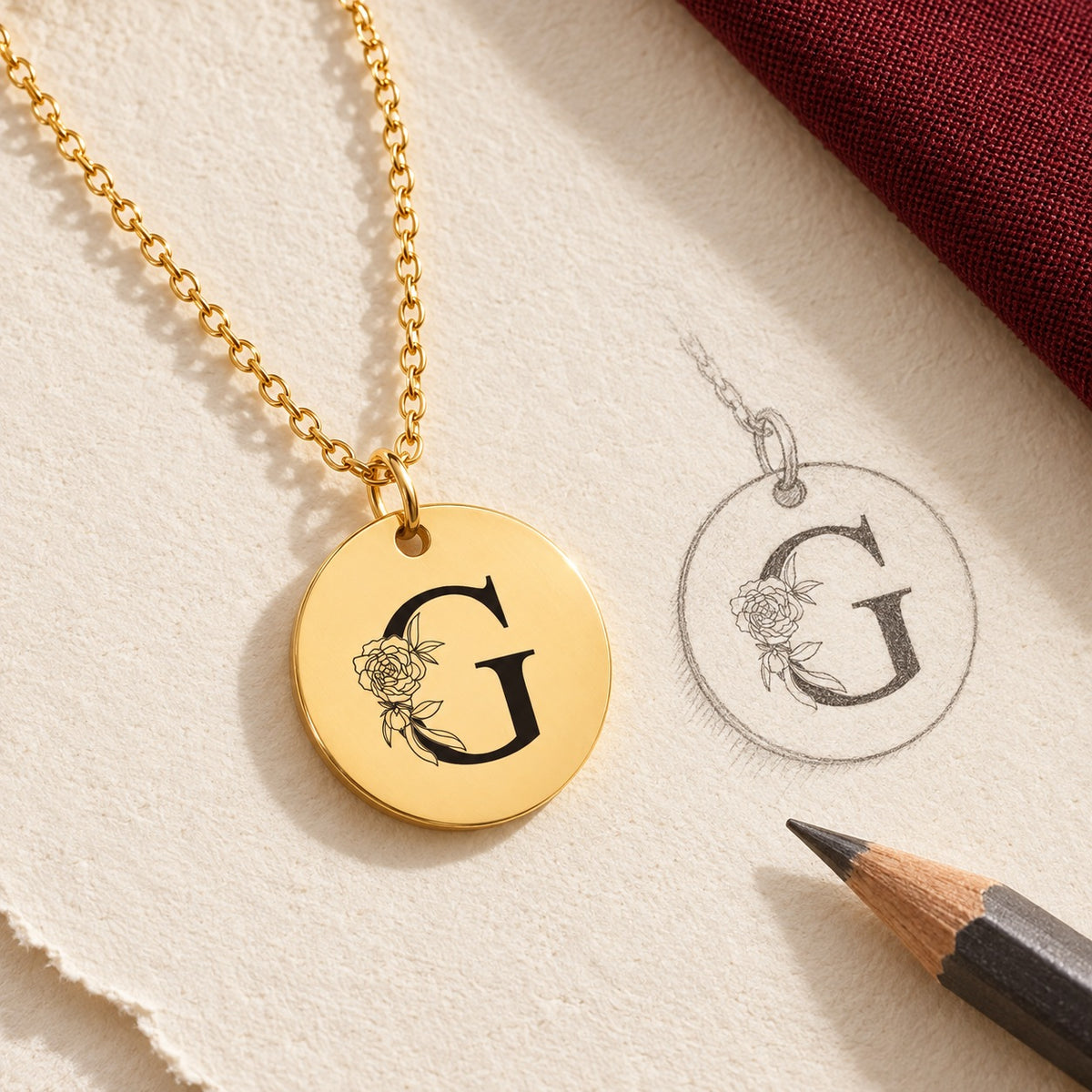 Collier initiale florale G personnalisé doré et étude au graphite du bijou sur papier ivoire.