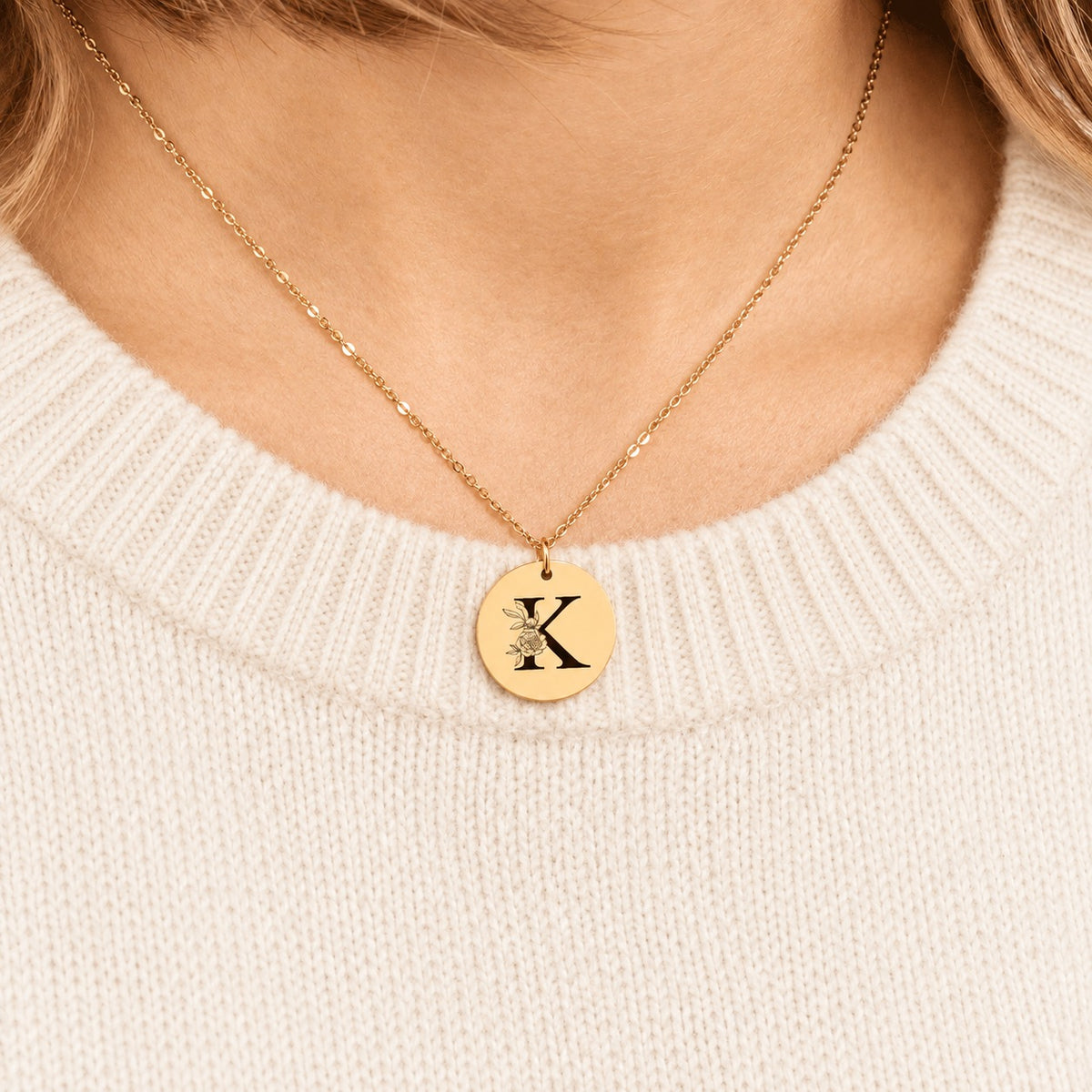 Collier initiale florale K personnalisé doré porté au cou, médaille ronde gravée.