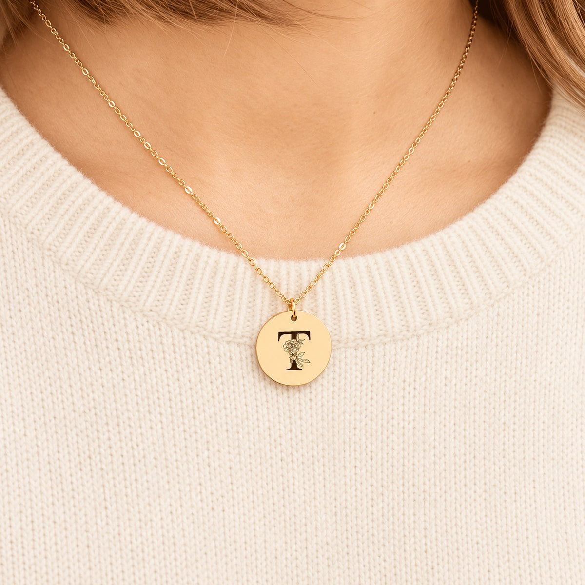 Collier initiale florale T personnalisé doré porté au cou, médaille ronde gravée.