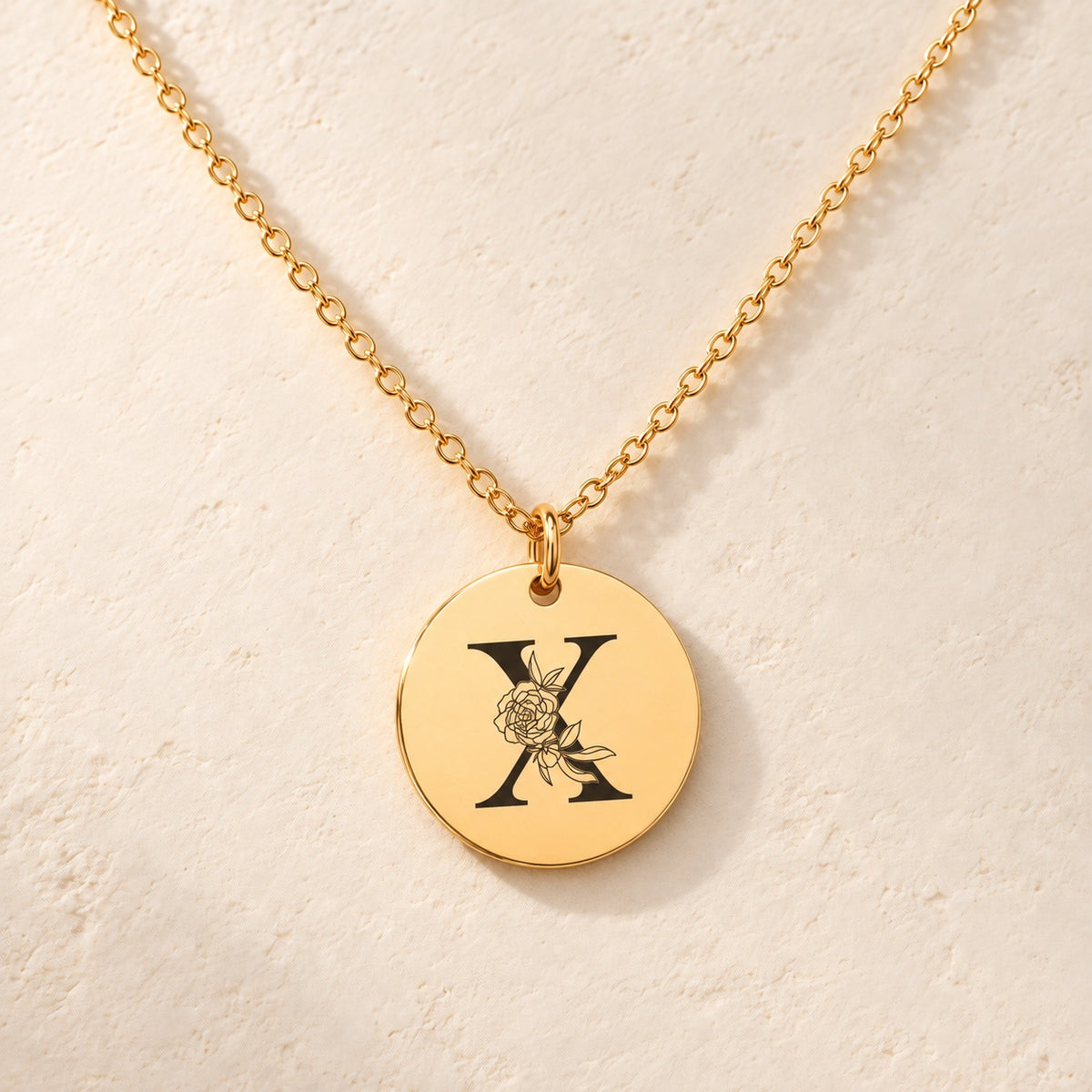 Détail de la médaille ronde dorée avec initiale X et fleurs.
