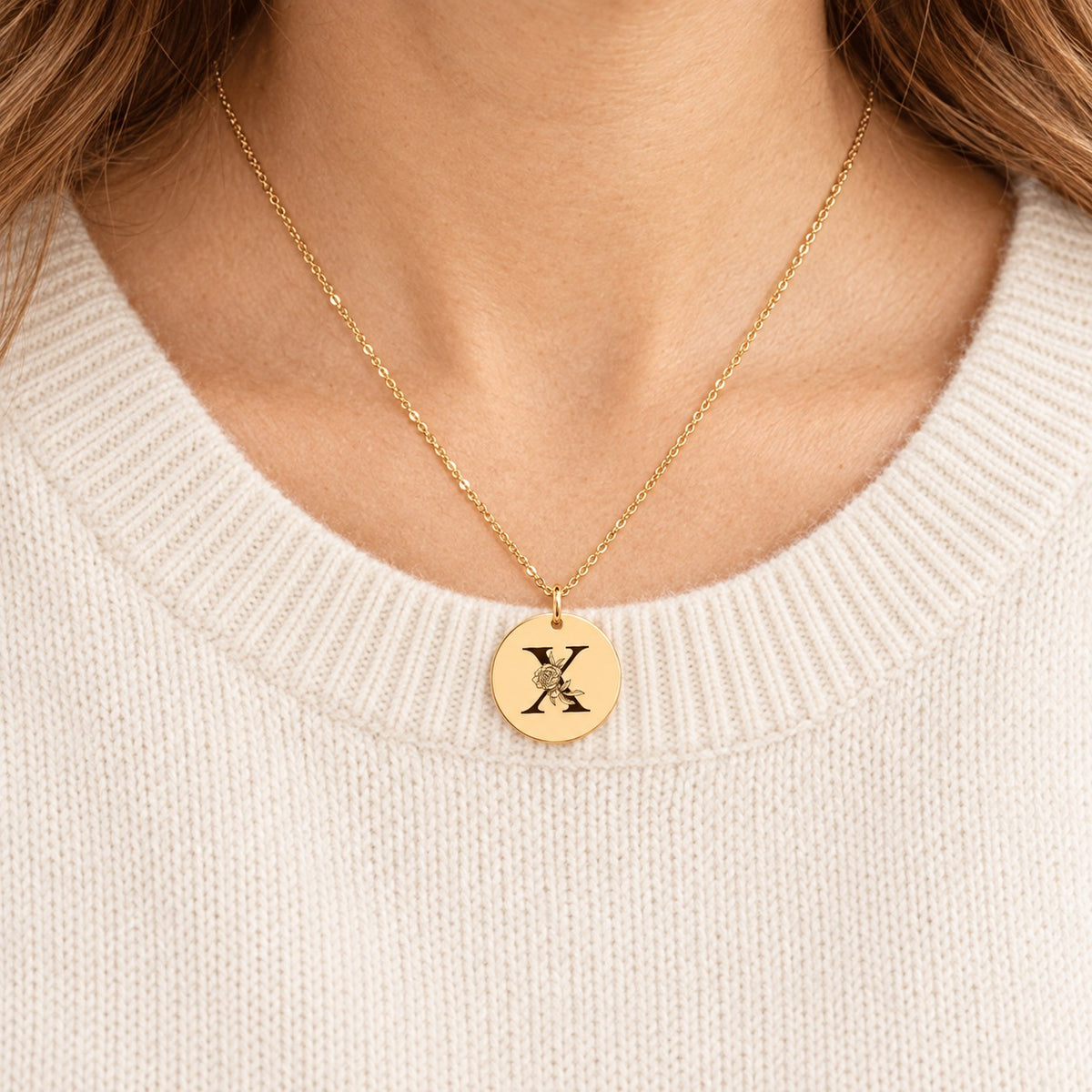 Collier initiale florale X personnalisé doré porté au cou, médaille ronde gravée.