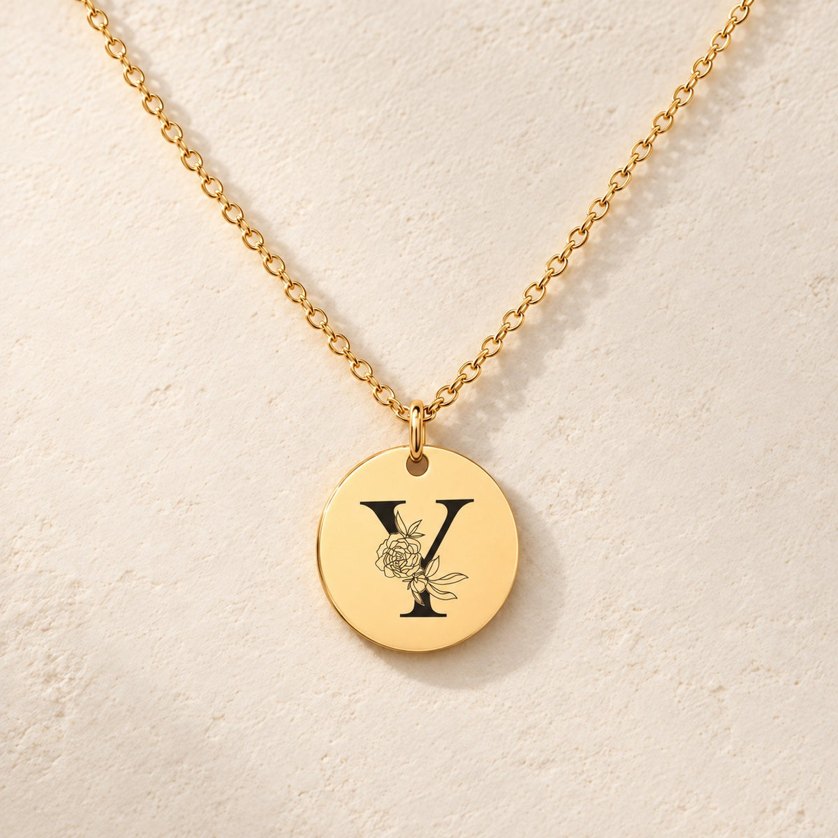Collier initiale florale Y personnalisé doré, médaille ronde gravée avec initiale Y et fleurs, sur fond ivoire.