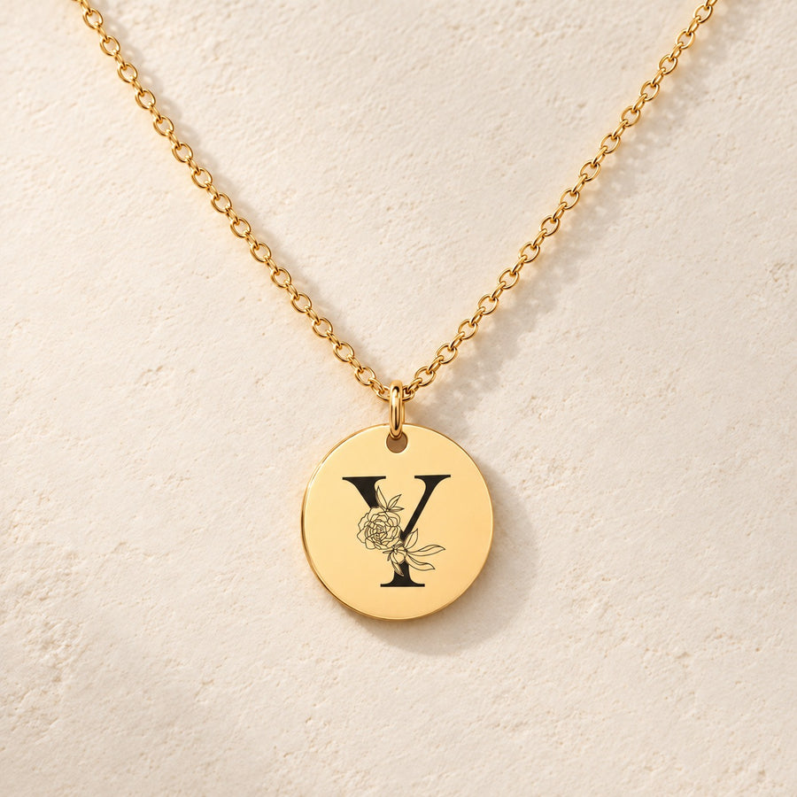 Collier initiale florale Y personnalisé doré, médaille ronde gravée avec initiale Y et fleurs, sur fond ivoire.