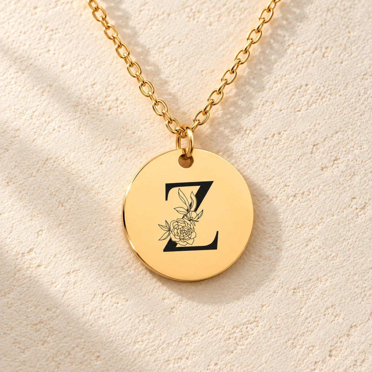 Détail de la médaille ronde dorée avec initiale Z et fleurs.