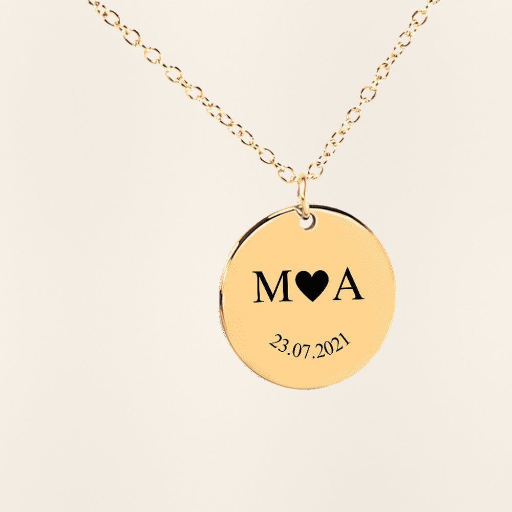 Collier Initiales Entrelacées Personnalisé (Etched In Time) en finition dorée, exemple de gravure sur fond ivoire texturé.