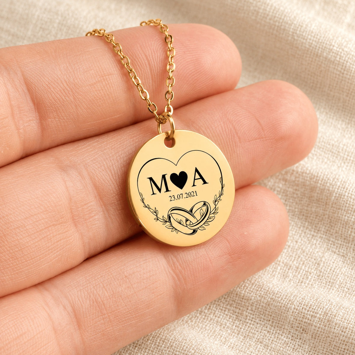 Collier initiales entrelacées Eternal Love personnalisé doré tenu en main, détail de la gravure.