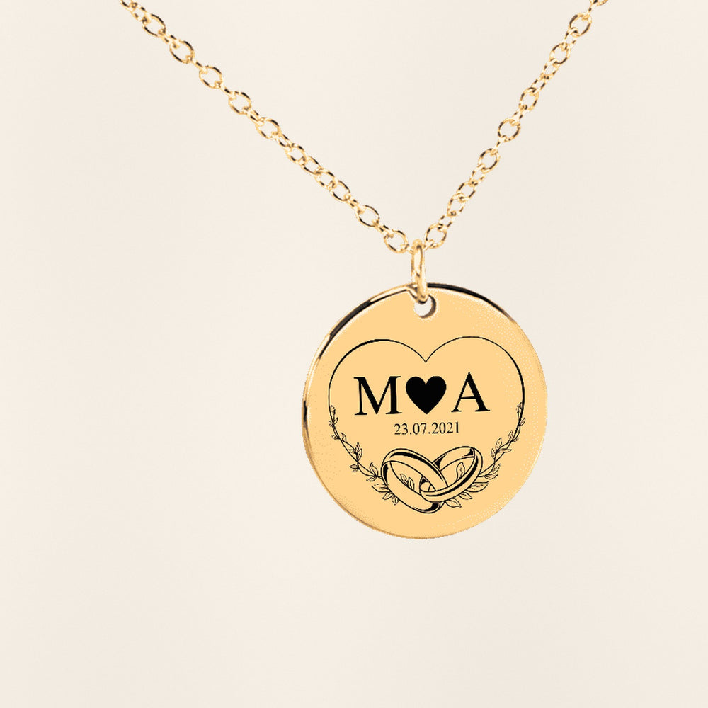 Collier Initiales Entrelacées Personnalisé (Eternal Love) en finition dorée, exemple de gravure sur fond ivoire texturé.