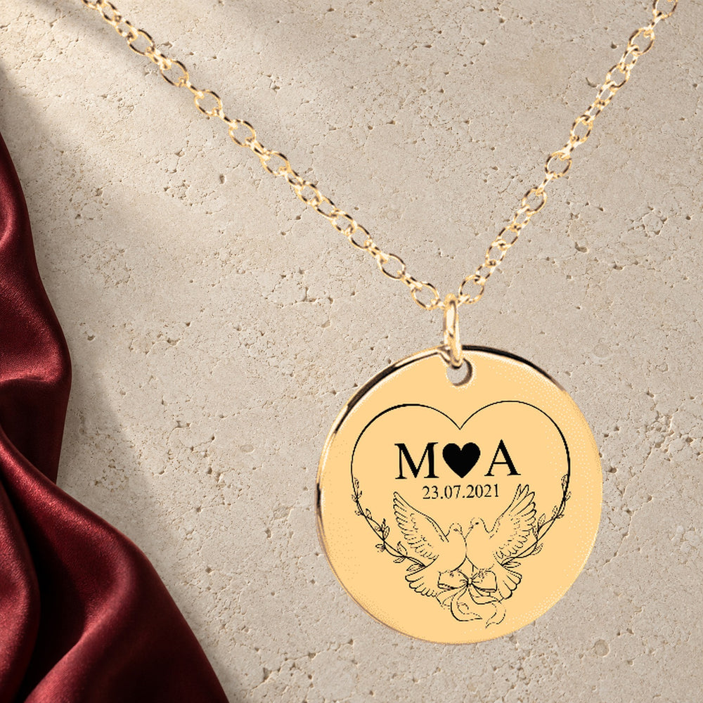 Collier Initiales Entrelacées Personnalisé (Timeless Bond) en finition dorée sur pierre claire, avec étoffe rouge sanguine ; exemple de personnalisation.