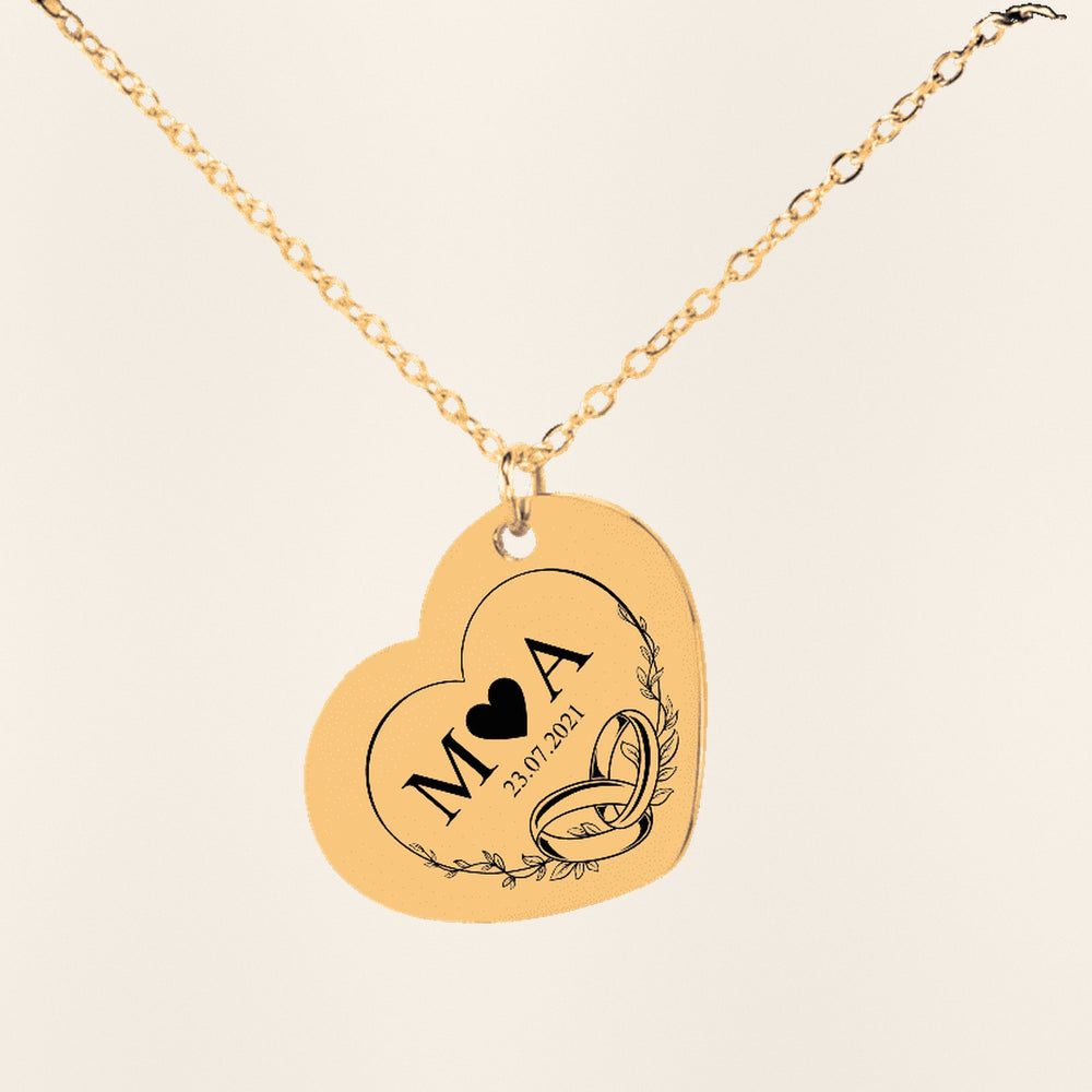 Collier Initiales Entrelacées Personnalisé (Timeless Bond Coeur) en finition dorée, exemple de gravure sur fond ivoire texturé.