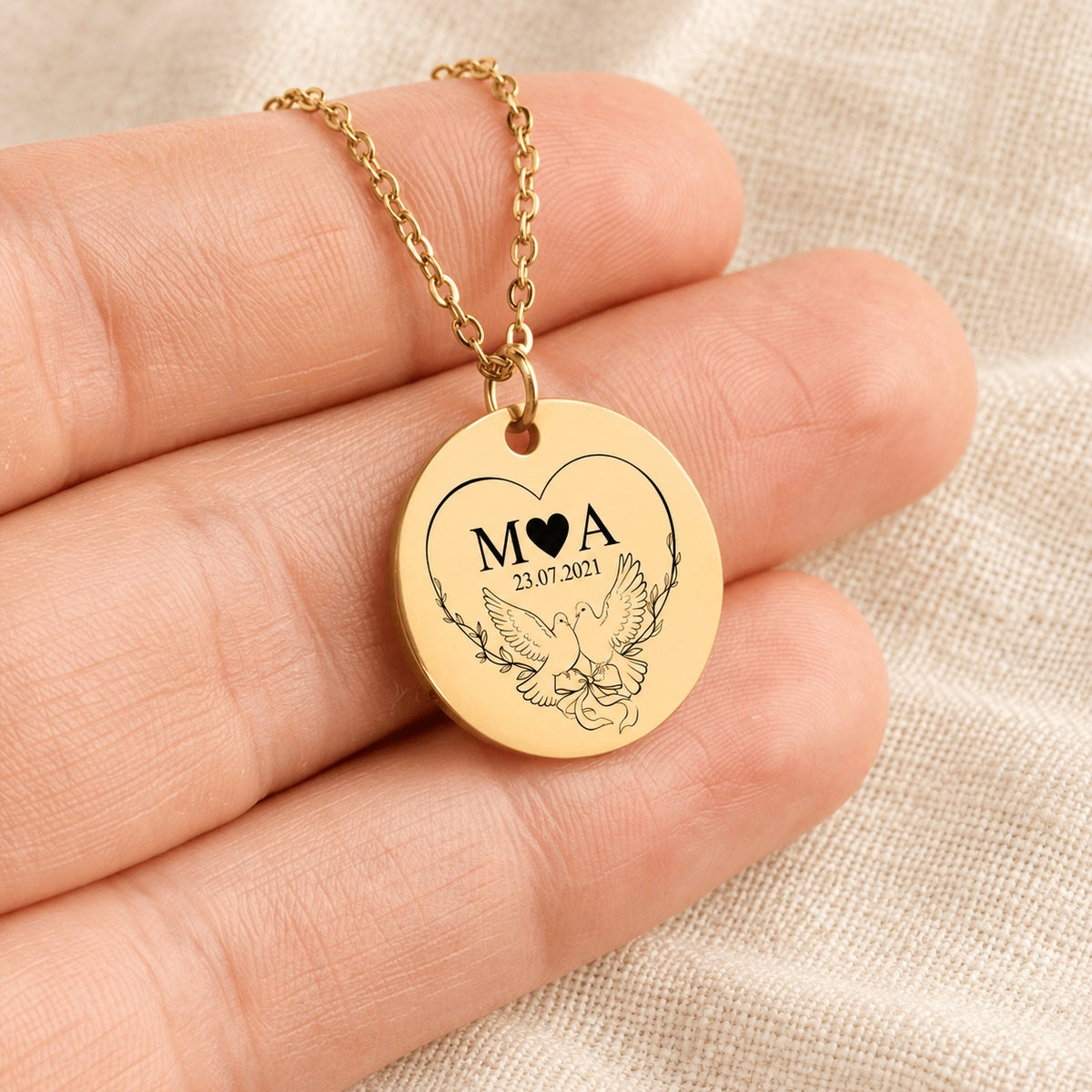 Collier Initiales Entrelacées personnalisé doré tenu en main, détail de la gravure.