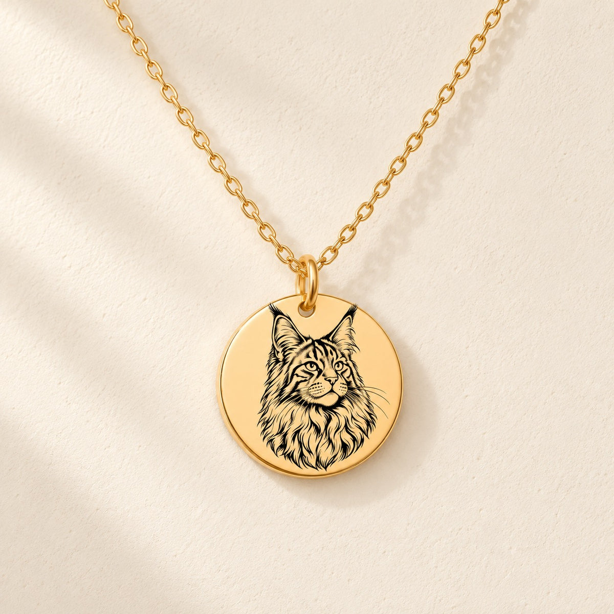 Collier Maine Coon doré avec portrait de Maine Coon gravé, sur fond ivoire.