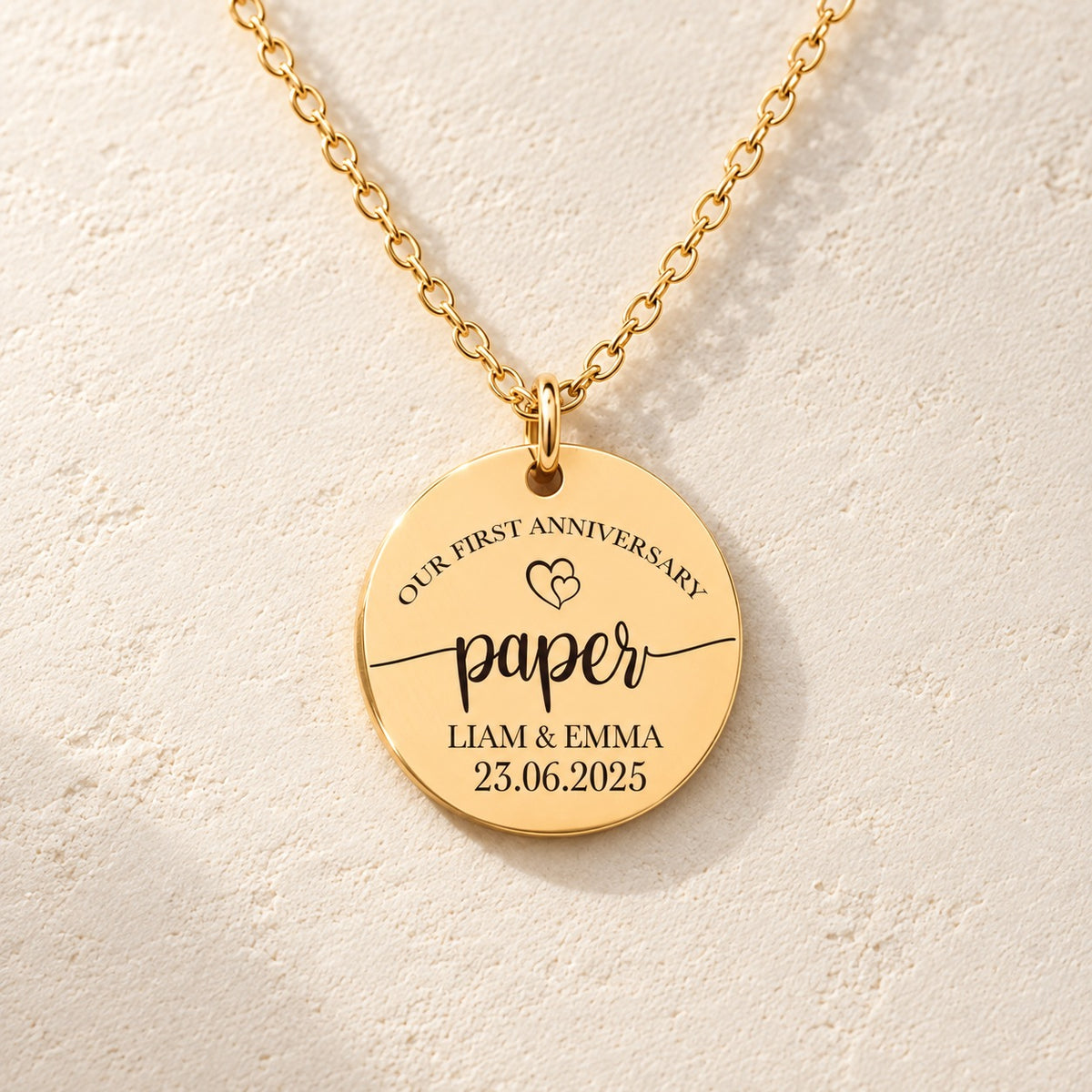 Détail de la médaille ronde dorée avec inscription « paper », prénoms Liam et Emma et date 23.06.2025.