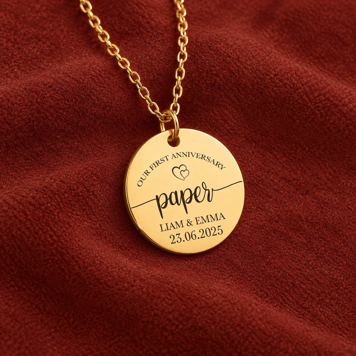 Médaille ronde dorée avec inscription « paper », prénoms Liam et Emma et date 23.06.2025, sur suédine rouge sanguine.