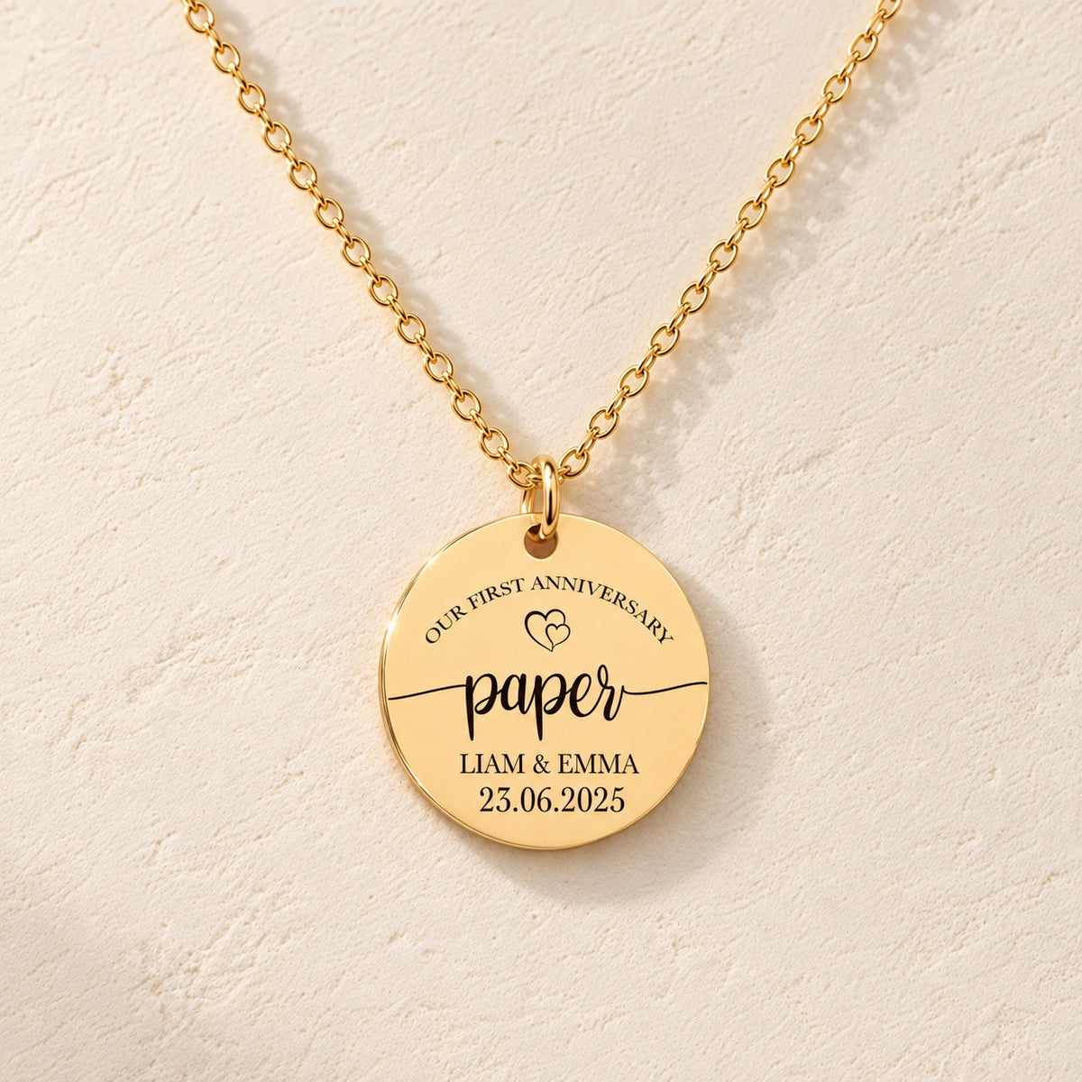 Collier Médaille Anniversaire de Mariage 1 an doré, médaille ronde gravée avec inscription « paper », prénoms Liam et Emma et date 23.06.2025, sur fond ivoire.