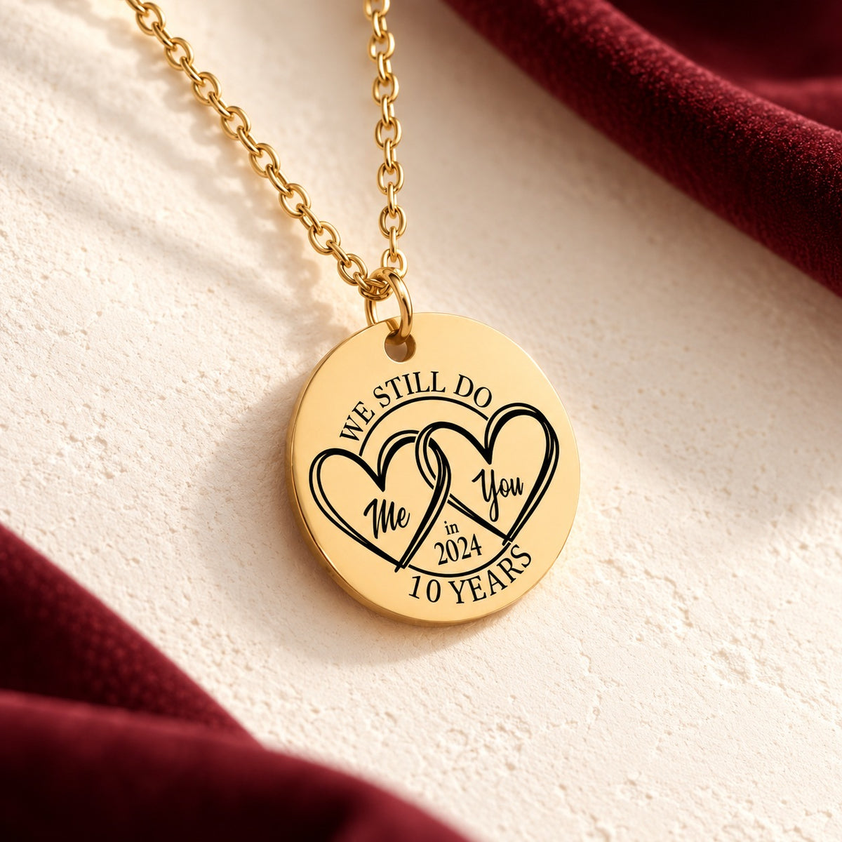 Détail du médaille ronde doré avec deux cœurs entrelacés et inscription « 10 YEARS », sur fond ivoire.