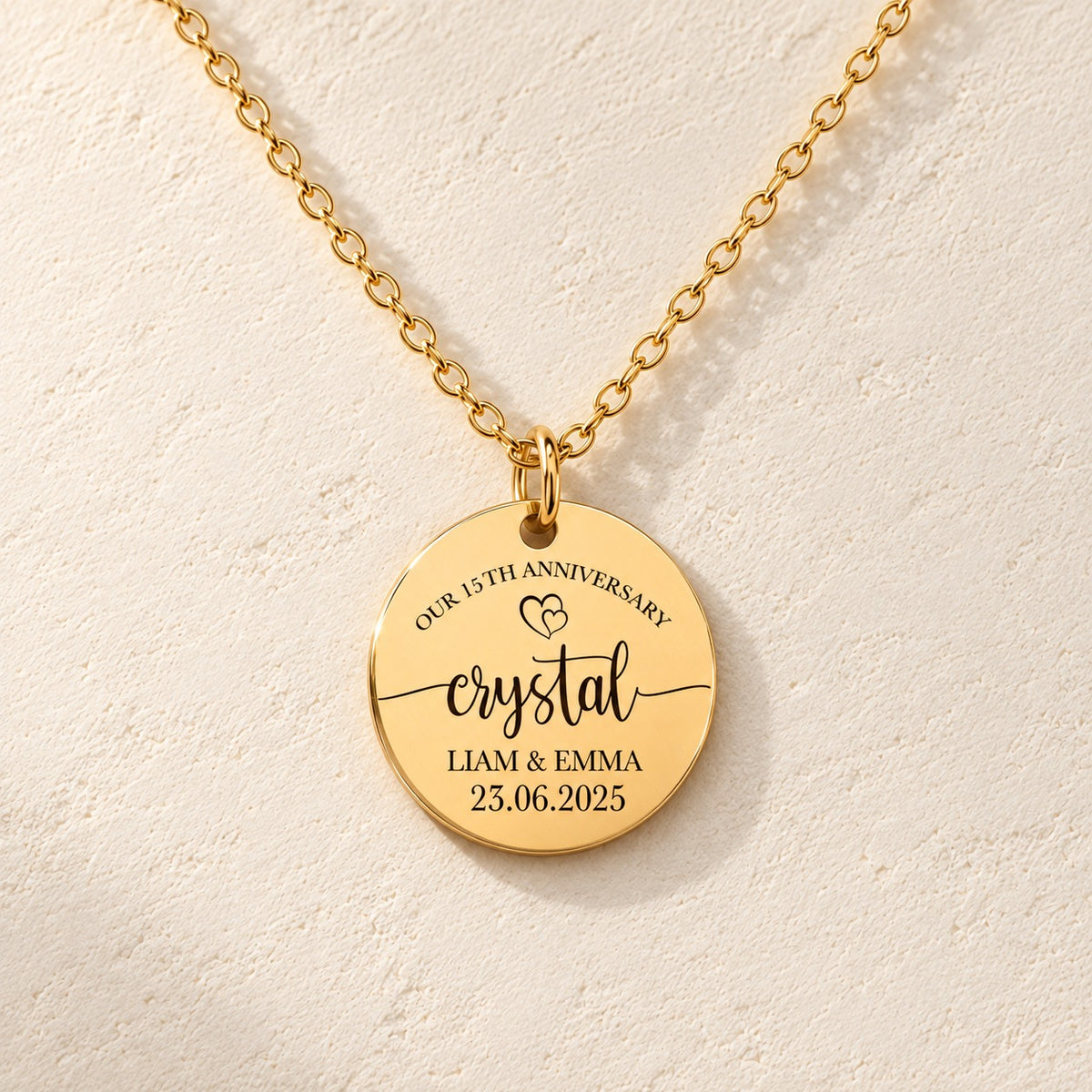 Détail de la médaille ronde dorée avec inscription « crystal », prénoms Liam et Emma et date 23.06.2025.
