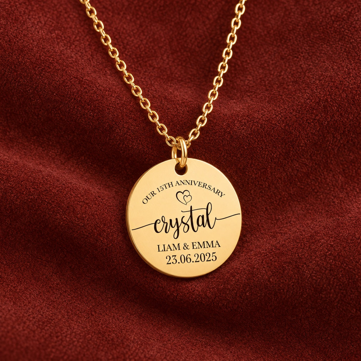 Médaille ronde dorée avec inscription « crystal », prénoms Liam et Emma et date 23.06.2025, sur suédine rouge sanguine.