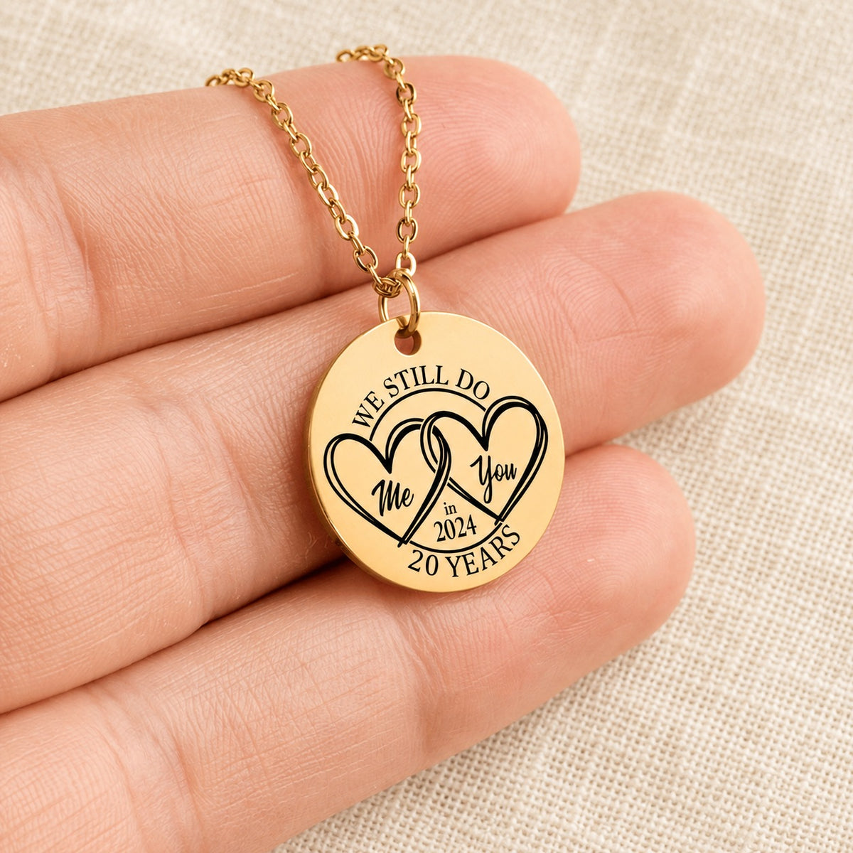 Collier Médaille Anniversaire de Mariage 20 ans doré tenu en main, détail de la gravure.