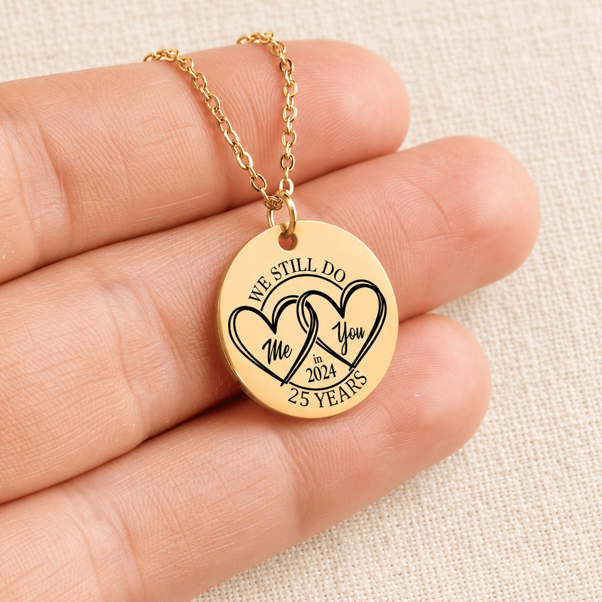 Collier Médaille Anniversaire de Mariage 25 ans doré tenu en main, détail de la gravure.