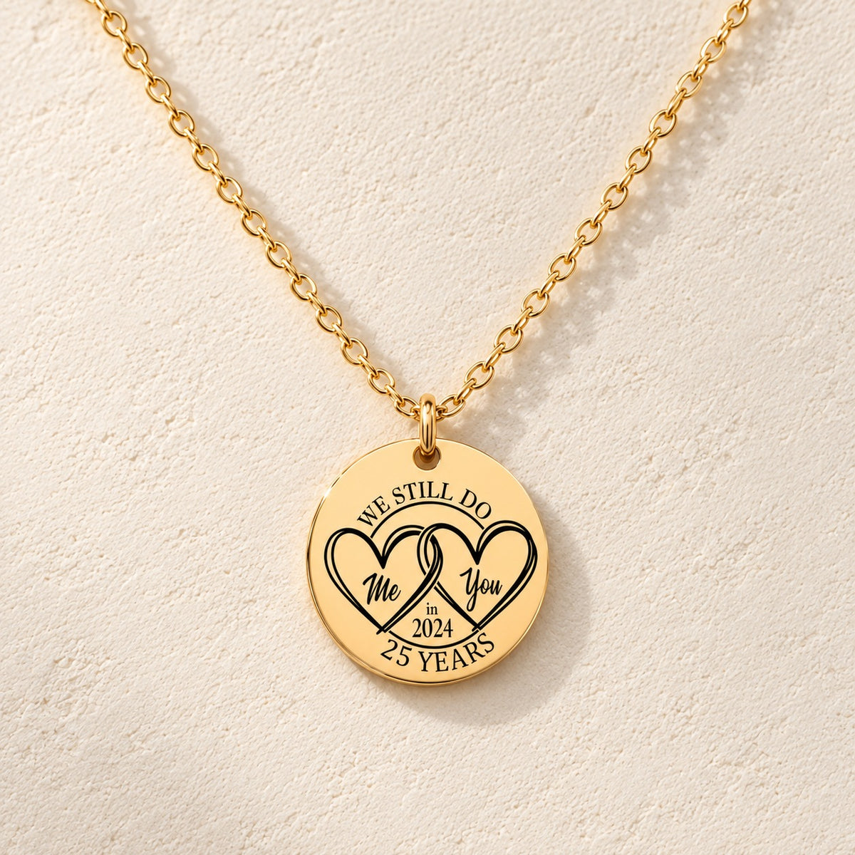 Collier Médaille Anniversaire de Mariage 25 ans doré, médaille ronde gravée avec deux cœurs et inscription « 25 YEARS », sur fond ivoire.