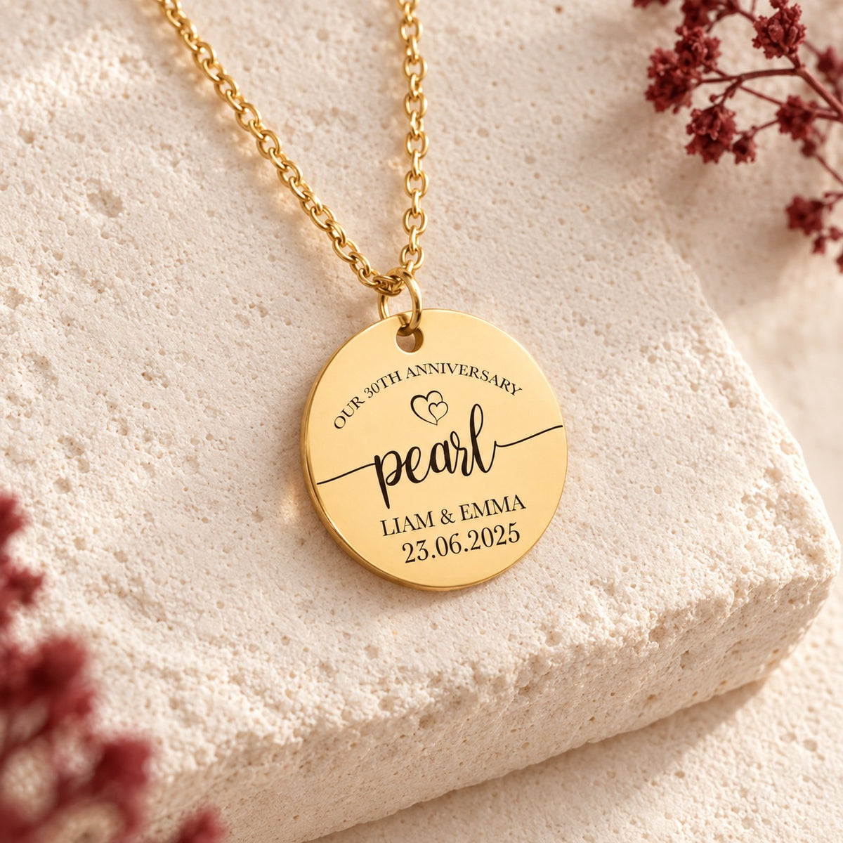 Détail de la médaille ronde dorée gravée avec inscription « pearl », prénoms Liam et Emma et date 23.06.2025.