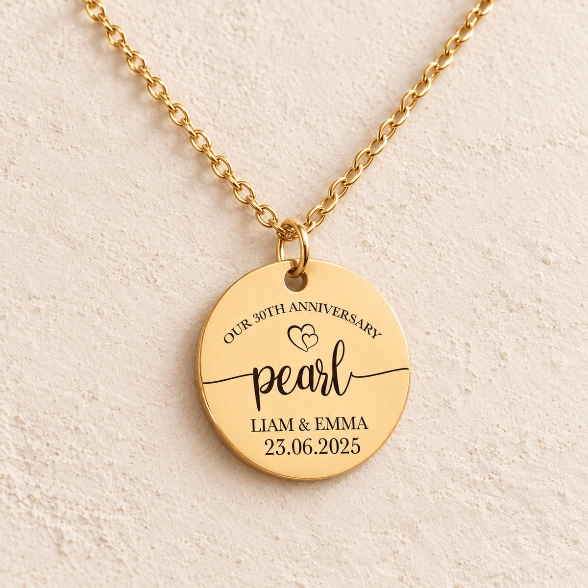 Collier anniversaire de mariage 30 ans doré, médaille ronde gravée avec inscription « pearl », prénoms Liam et Emma et date 23.06.2025, sur fond ivoire.