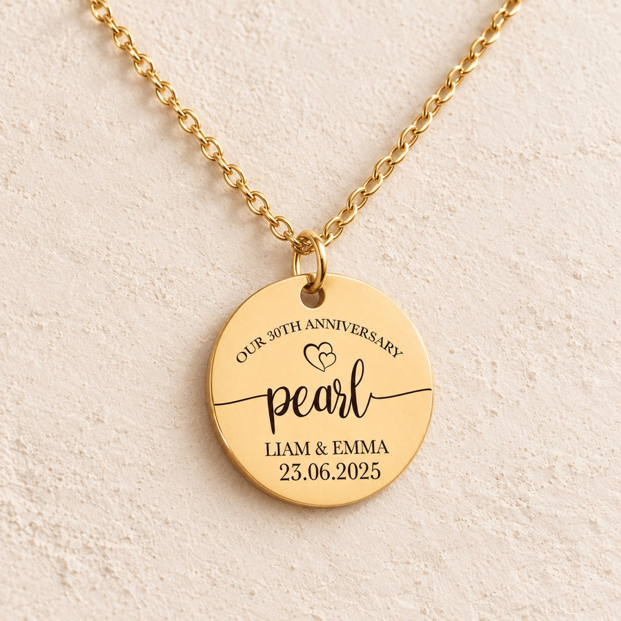 Collier anniversaire de mariage 30 ans doré, médaille ronde gravée avec inscription « pearl », prénoms Liam et Emma et date 23.06.2025, sur fond ivoire.